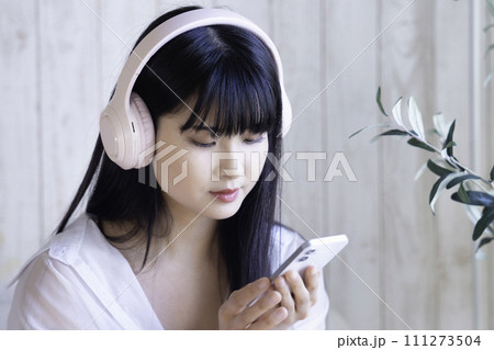 ヘッドホンでスマホの音楽を聴く若い女性 111273504
