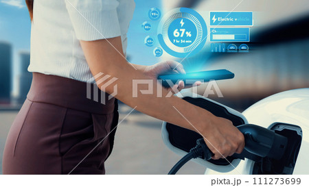 Modern woman insert EV charger to electric car port. Peruse 111273699