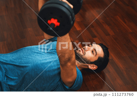 Athletic body and active sporty man lifting dumbbell at gaiety home exercise. 111273760