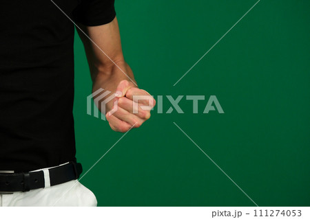 close-up on a green background clenched fist man aggression dissatisfaction space for text expression of negative emotions white jeans black T-shirt unrecognizable people guy chromakey 111274053