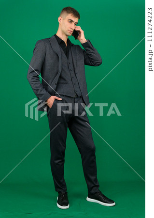 emotions of a handsome man guy on a green background chromakey close-up dark hair young man. phone in hand talk dial SMS online call gadget boss work advertising emotions of a handsome man guy on a green background chromakey close-up dark hair young man. phone in hand talk dial SMS online call gadget boss work advertising 111274223
