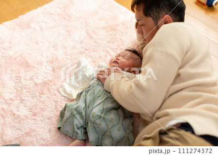 ぐずる子供を寝かしつけるパパ 111274372