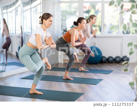 Girl teacher conducts lesson, training for girls in yoga studio and performs eagle pose 111275337