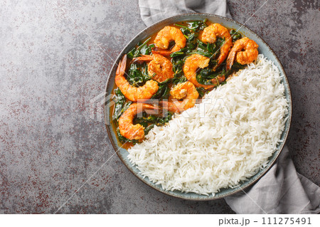 Palak Prawn made of spinach, cream, spices, tomato and ginger served with rice closeup on the plate. Horizontal top view Palak Prawn made of spinach, cream, spices, tomato and ginger served with rice closeup on the plate. Horizontal top view 111275491