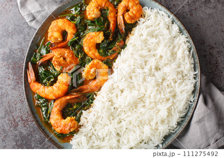 Spinach Shrimp Curry or Jheenga Palak cooked in a spinach, cream, spices, tomato and ginger served with rice closeup on the plate. Horizontal top view 111275492