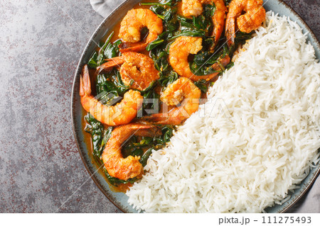 Shrimp curry cooked in a spinach, cream, spices, tomato, and ginger served with rice closeup on the plate. Horizontal top view 111275493