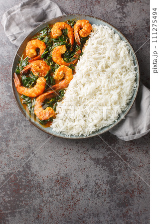 Delicious Indian prawn and spinach curry served with rice closeup on the plate. Vertical top view 111275494