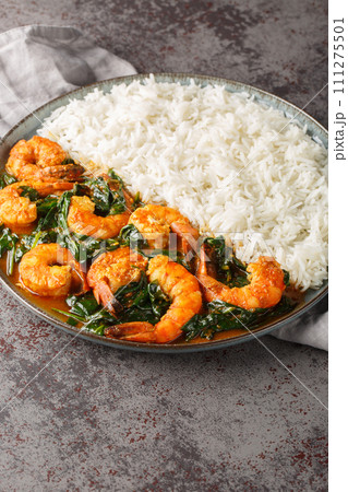 Shrimp Saag is an flavorful curry made with juicy prawn, onion, garlic, ginger, spinach and aromatic spices served with rice closeup on the plate. Vertical 111275501
