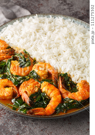 Delicious Indian prawn and spinach curry served with rice closeup on the plate. Vertical 111275502