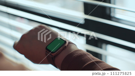 Woman making gestures on a wearable smartwatch computer device, close up. Smart watch with a green screen chroma key. 111275825