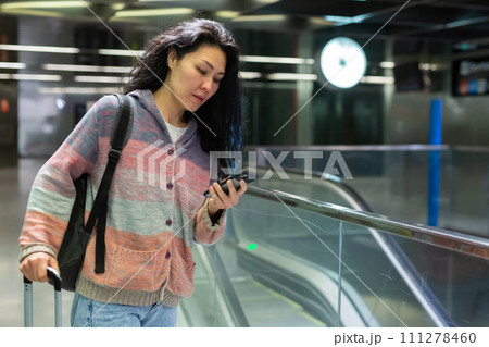 Woman with backpack and suitcase walking in subway escolator Woman with backpack and suitcase walking in subway escolator 111278460