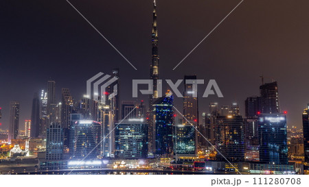 Aerial view to Dubai Business Bay and Downtown with the various skyscrapers and towers all night timelapse 111280708