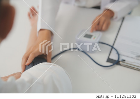 Male doctor uses a blood pressure monitor to check the body pressure and pulse of the patients who come to the hospital for check-ups, Medical treatment and health care concept. Male doctor uses a blood pressure monitor to check the body pressure and pulse of the patients who come to the hospital for check-ups, Medical treatment and health care concept. 111281302