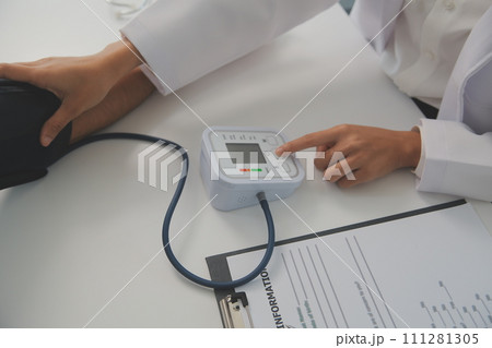 Male doctor uses a blood pressure monitor to check the body pressure and pulse of the patients who come to the hospital for check-ups, Medical treatment and health care concept. 111281305