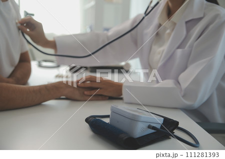 Young doctor is using a stethoscope listen to the heartbeat of the patient. Shot of a female doctor giving a male patient a check up 111281393