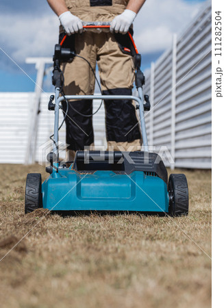 Scarifying lawn with scarifier, Man gardener scarifies the lawn and removal of old grass 111282504