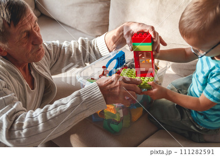 Elderly grandpa or grandfather plays with his little grandson Elderly grandpa or grandfather plays with his little grandson 111282591