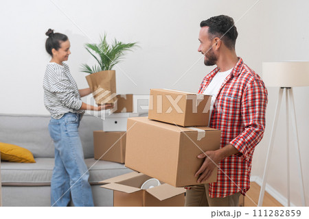 Positive couple of man and woman pack boxes with things getting ready to move to new place and start exciting new life together filled with joy and anticipation 111282859