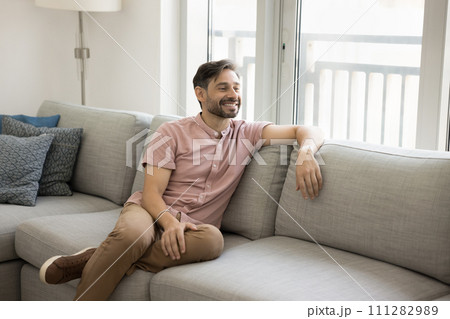 Positive thoughtful relaxed middle aged man sitting on comfortable couch Positive thoughtful relaxed middle aged man sitting on comfortable couch 111282989