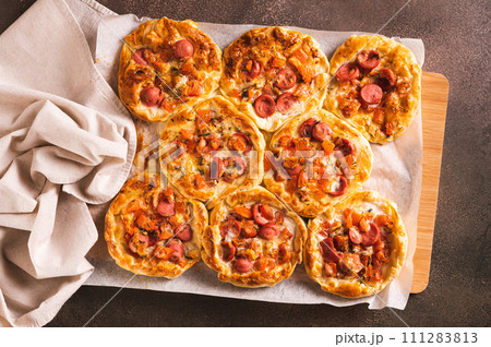 Fresh pizza pot pies with tomatoes, cheese and sausages on a wooden board top view Fresh pizza pot pies with tomatoes, cheese and sausages on a wooden board top view 111283813