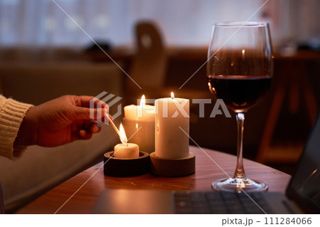 Side view closeup of unrecognizable mature Black woman lighting candles on wooden table enjoying relaxing evening at home copy space Side view closeup of unrecognizable mature Black woman lighting candles on wooden table enjoying relaxing evening at home copy space 111284066