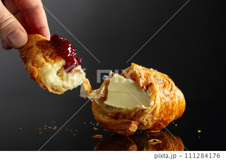 Fresh baked croissant with butter and raspberry jam. 111284176