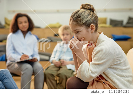 Side view portrait of depressed teen girl in support group meeting for childrenwith copy space 111284233