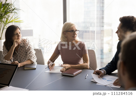 Confident elder businesswoman talking to younger business partners 111284516