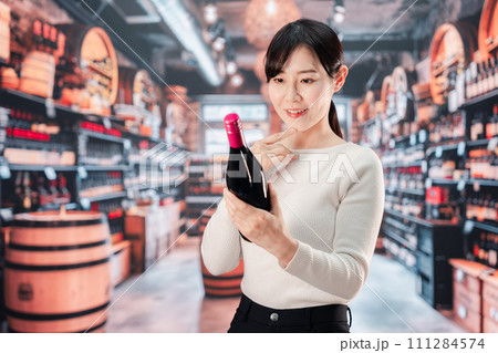 ワインショップでワインを選ぶ若い女性 ワインショップでワインを選ぶ若い女性 111284574