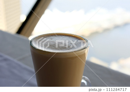 Milk coffee in glass cup and spoon on grey table Milk coffee in glass cup and spoon on grey table 111284717