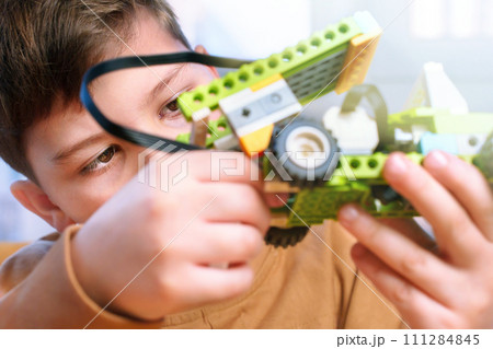Little boy makes robot toy car. Smart boy assemble constructor kids workshop. Smart child science class robotics kids technology child constructor robotics learning and development kids stem education 111284845