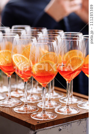Glasses of alcoholic Aperol Spritz cocktail. Italian aperitif with ice, aperol, prosecco, soda and slice of orange in large round glasses on party. Celebration concepts festive days. 111285389