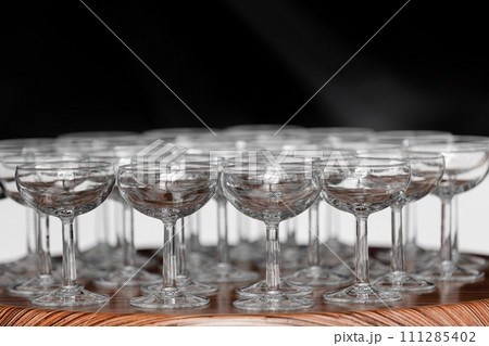 Many elegant empty glasses of wine or champagne on the wooden table in wedding day. Set of blank empty glasses displayed in rows. Preparation for the holiday 111285402