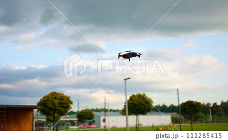 Hovering drone flying upward on a cloudy sky backdrop. copter flying . Hovering drone flying upward on a cloudy sky backdrop. copter flying . 111285415