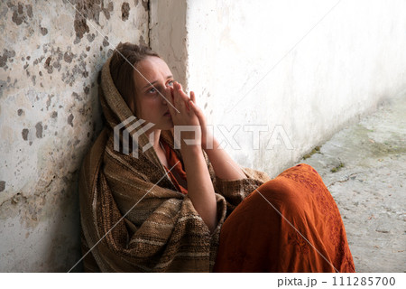 A girl in poor clothes sits on the ground A girl in poor clothes sits on the ground 111285700