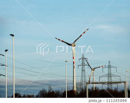 Wind farm park and high voltage towers next to a road in Austria in sunny weather. 111285899