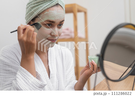 Post-Bath Luxury: Towel-draped, she applies a facial mask for anti-aging, moisture, and perfecting her skin.  111286022