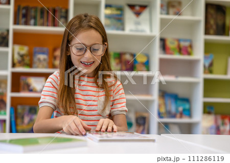 Brown haired sitting school library reading preparing for lessons. Brown haired sitting school library reading preparing for lessons. 111286119