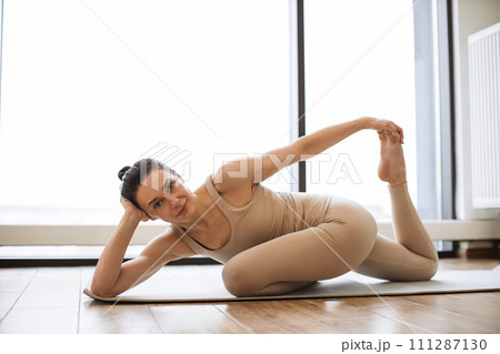 Caucasian lady looking at camera in athletic wear doing front hip opening asana. Caucasian lady looking at camera in athletic wear doing front hip opening asana. 111287130