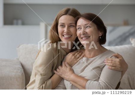 Loving tender daughter hugging her attractive pensive older mother Loving tender daughter hugging her attractive pensive older mother 111290219