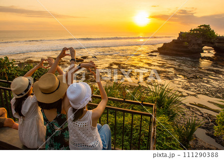 Happiness tourist enjoy their holiday with the beautiful sunset over Pura Batu Bolong an iconic Hinduism sea temple in Bali, Indonesia. 111290388