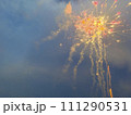Red and orange fireworks against sunset sky. 111290531