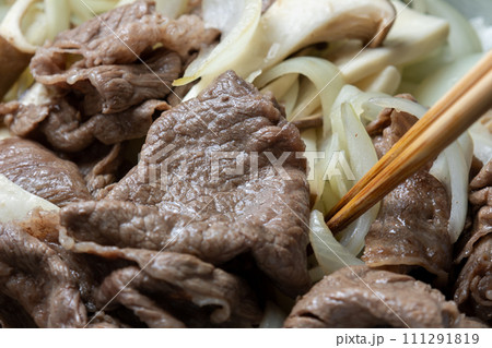 牛肉と玉ねぎとエリンギをフライパンで炒める調理シーン。 111291819