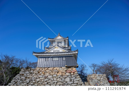 青空バックに見上げる古い時代の野面積みの石垣の城の情景 111291974