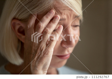 Close up unhappy mature woman crying, touching forehead, feeling unwell Close up unhappy mature woman crying, touching forehead, feeling unwell 111292767