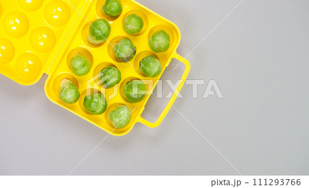 Raw organic Brussel sprouts in yellow container on grey background, top view. Flat lay, overhead, from above. Copy space. 111293766