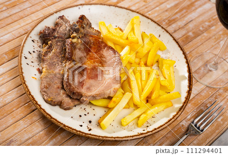 Pork chop with French fries on a plate. 111294401