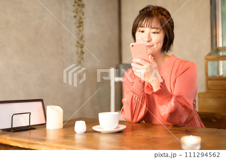 カフェでスマホを見る女性　 111294562