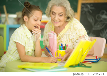Grandmother with cute little girl doing homework together 111294721