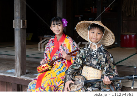 沖縄の民族衣装を着て三線を引く日本人の子ども 111294963
